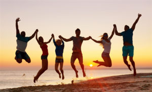 Eine Gruppe von Menschen, die im Sonnenuntergang am Strand jauchzend hüpfen