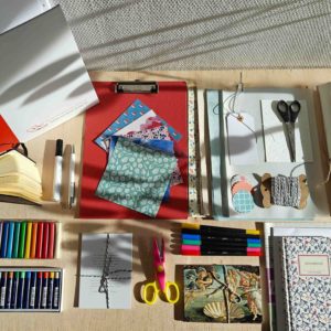 Verschiedene Kursmaterialien werden gezeigt: Ordner, Papier, Bastelschere, Kladde, Stifte, Ölkreide etc.